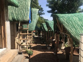 A courtyard with thatched-roof structures, wooden staircases, and potted plants.