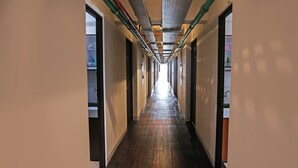 A long, narrow hallway with wooden flooring and doors on both sides. - OYO 92317 Apartment Riverview By Alima View (Cikarang)