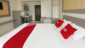 A hotel room with a large bed, a desk, and a kitchenette. - OYO 92317 Apartment Riverview By Alima View (Cikarang)