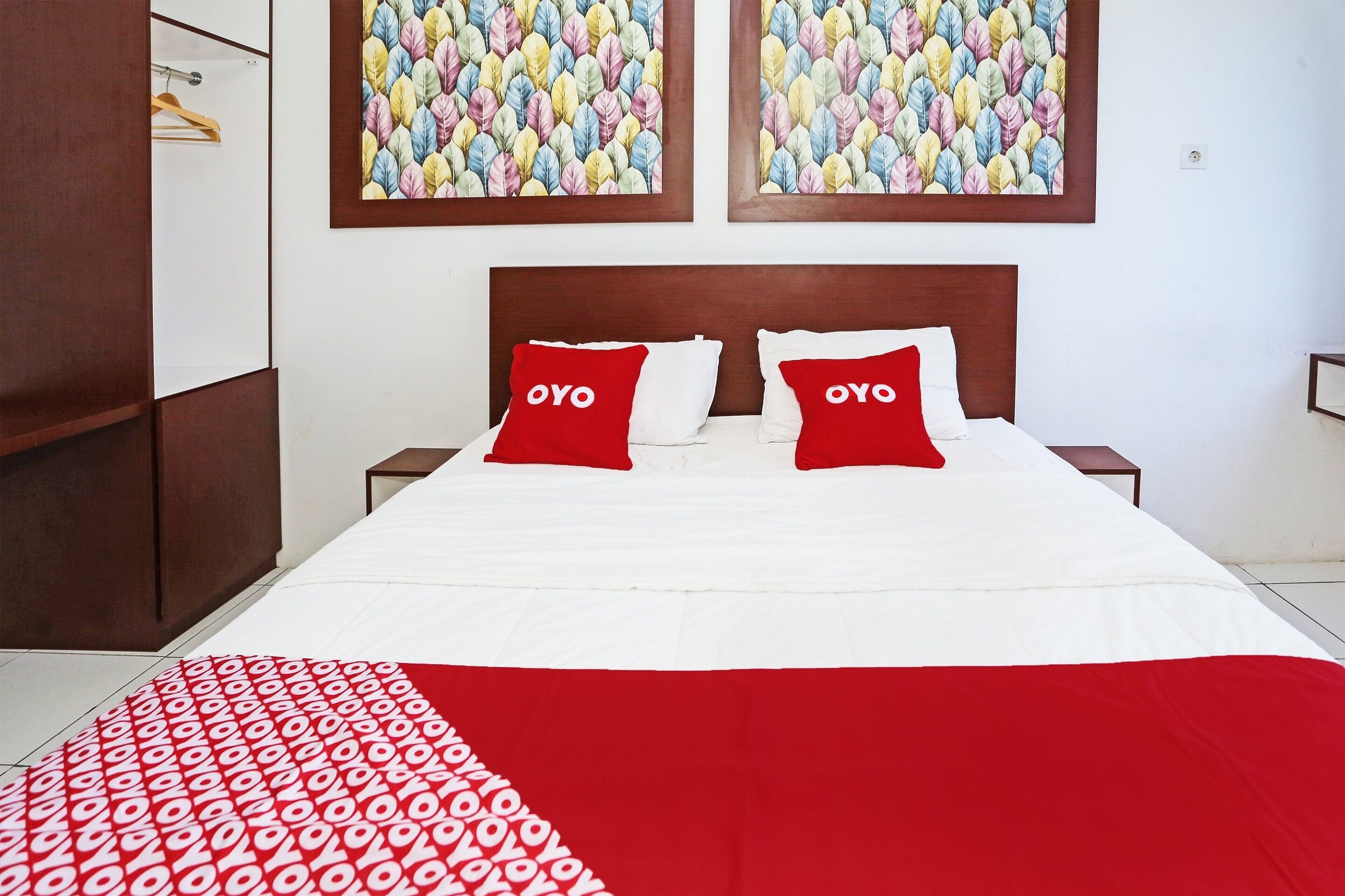 A neatly made bed with two red pillows, a white bedspread, and a red and white patterned blanket.