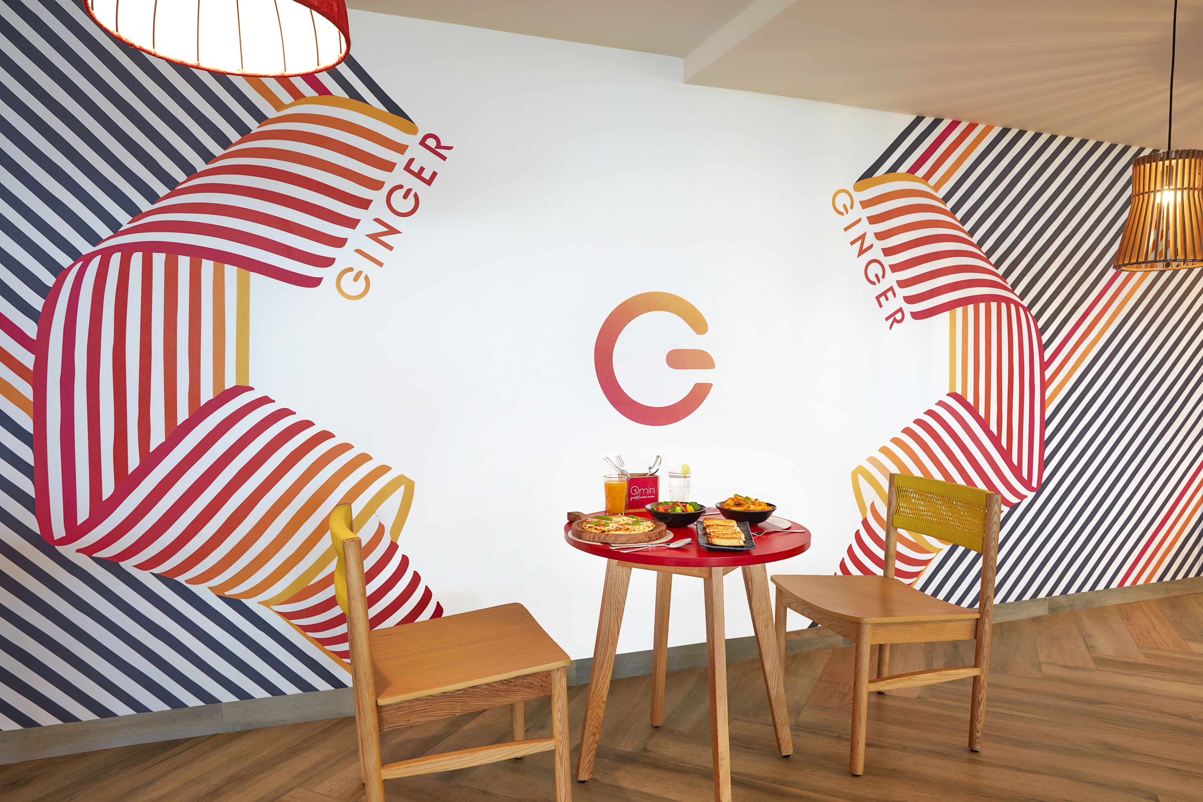 Ein Essbereich mit einem roten Tisch, zwei Holzstühlen und einer Wand mit einem Streifenmuster-Lebkuchenmann-Design.