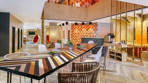A modern dining area with a long table, chairs, and a staircase leading to an upper level. - Ginger Noida Sector 133 (Noida)