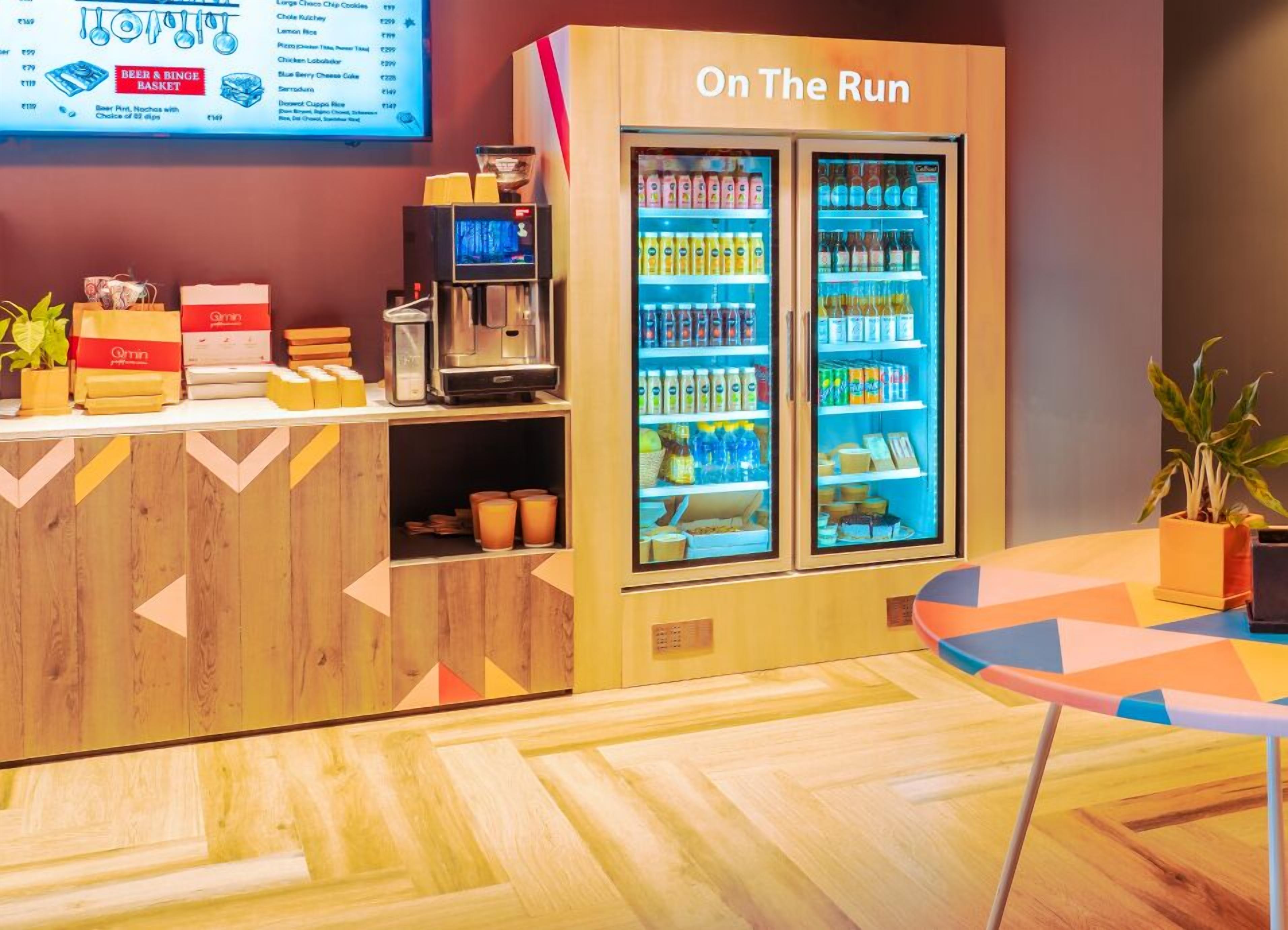 Una barra con una máquina de café, un refrigerador de bebidas y un panel de menú.