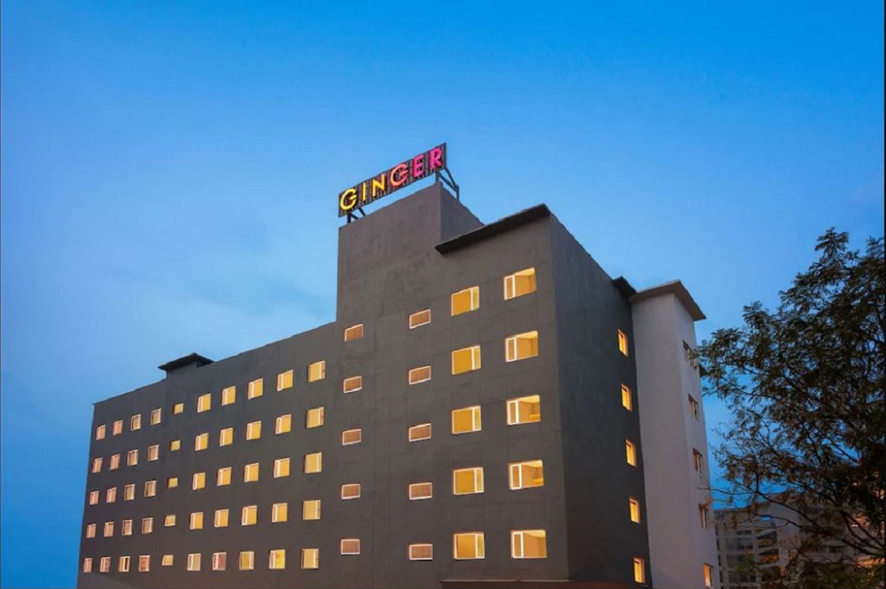 A hotel with a modern design, featuring a prominent 'GINGER' sign on the roof.