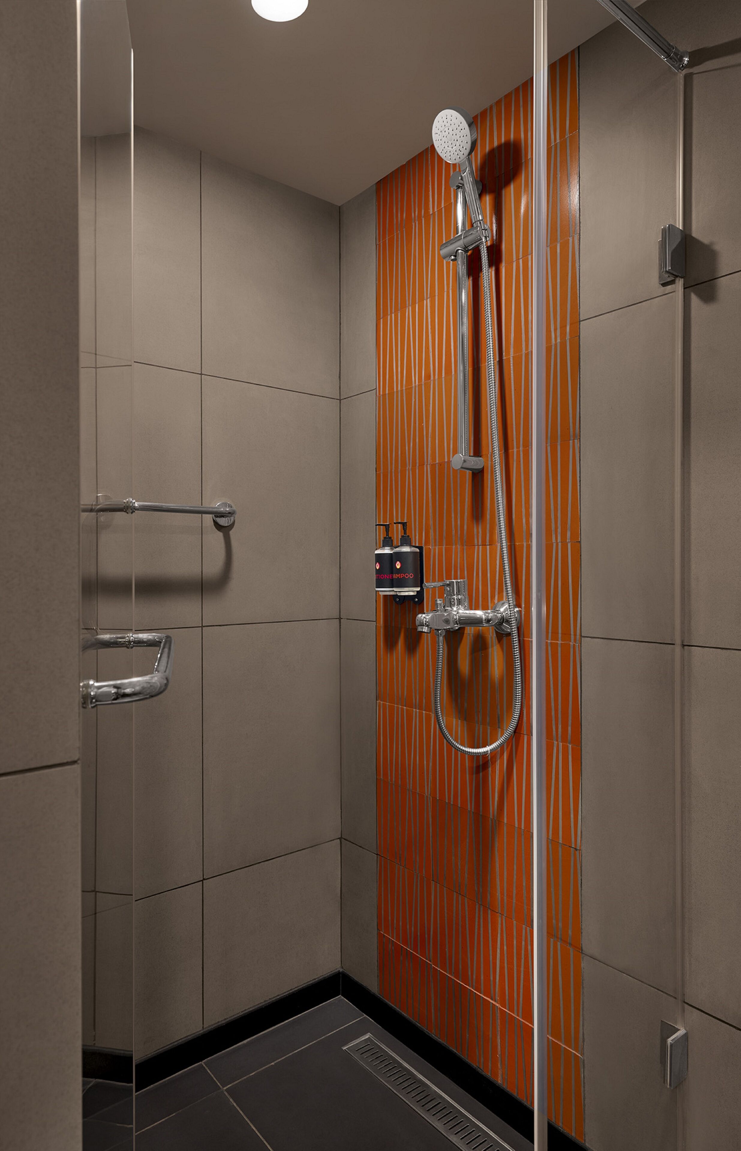 A modern shower with a wooden panel wall, a handheld showerhead, and a handheld shower attachment.