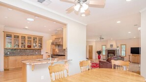 A spacious kitchen with wooden cabinets, a granite countertop, and a central island with chairs. - Guinda's Finest Nature Get-Away! (Guinda)