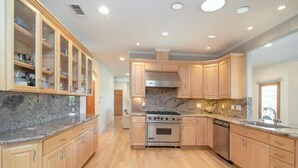 A kitchen with wooden cabinets, granite countertops, a stainless steel stove, and a dishwasher. - Guinda's Finest Nature Get-Away! (Guinda)