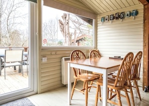 A dining area with a wooden table and chairs, a window with a view of trees, and a wall with numbered hooks.