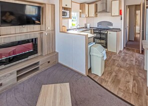 A compact kitchen with a TV, microwave, stove, and small island.