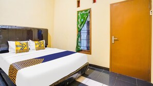 A hotel room with a bed, a window with a curtain, an air conditioner, and a door. - OYO Life 3005 Kost Rumaisha Syariah (Bandar Lampung)