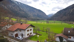 Une maison de campagne avec un toit recouvert de tuiles rouges, une façade blanche et un champ verdoyant en arrière-plan.