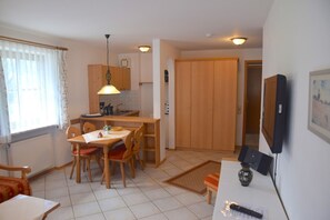 Eine kleine Küche mit Holdekor, einem Esstisch mit Stühlen, einer Pendelleuchte und einem kleinen Kühlschrank.