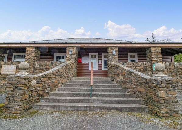 A stone building with a wooden exterior, a set of stone steps leading to a door, and a signboard.