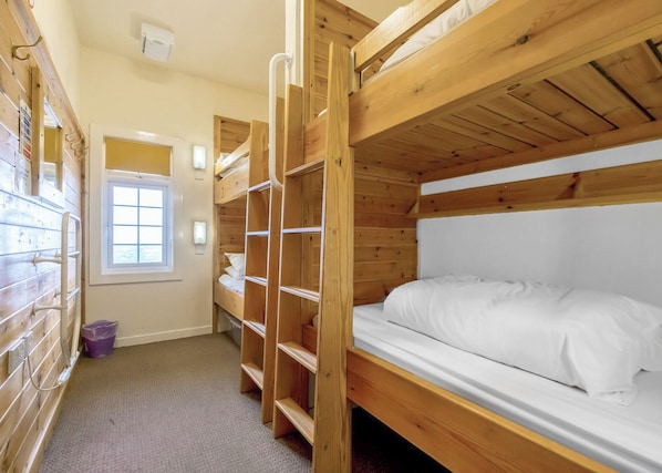 Une chambre avec un lit superposé, une fenêtre, un radiateur fixé au mur et une porte.