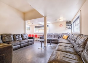 Un espace détente moderne avec des canapés en cuir, une petite table ronde et des chaises rouges.