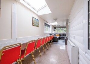 Ein Korridor mit einer Reihe roter Stühle, einem Sofa und einem Gemälde an der Wand.