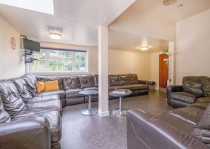 Ein modernes Wohnzimmer mit Ledersofas, einem kleinen runden Tisch und einem Fenster mit Blick auf Grünflächen.