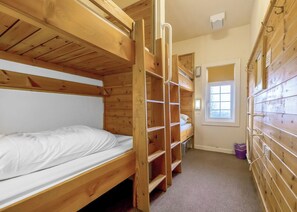 A bunk bed room with a window, wooden walls, and a carpeted floor.