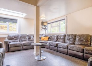 A living room with a sectional sofa, a round coffee table, and a TV mounted on the wall.