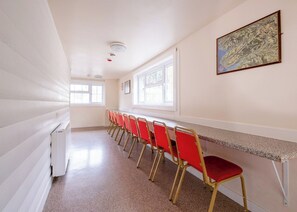 Ein Konferenzraum mit langem Tisch, roten Stühlen, Fenstern und einer Karte an der Wand.