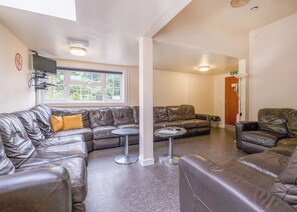 A modern living room with leather sofas, a small round table, and a window with a view of greenery.