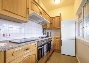 A kitchen with wooden cabinets, a stainless steel range, and a white refrigerator.