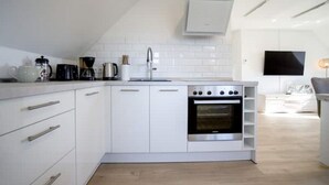 Eine moderne Küche mit weißen Schränken, einem eingebauten Backofen und einer Kaffeestation.