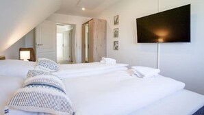 Ein Hotelzimmer mit drei Betten, einem Wand-Flachbildfernseher und einer Deckenleuchte.