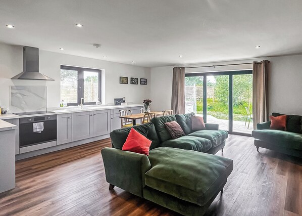 A modern kitchen with grey cabinets, a built-in oven, and a large window.