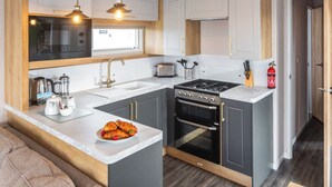 A modern kitchen with a central island, built-in oven, and a microwave. - 3 bedroom accommodation in Holywell Bay (Holywell Bay)