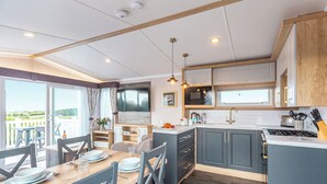 A modern kitchen with a dining area, large windows, and a view of the outdoors. - 3 bedroom accommodation in Holywell Bay (Holywell Bay)
