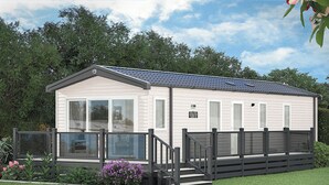 A single-story mobile home with a covered porch, a small deck, and a fenced yard. - 3 bedroom accommodation in Holywell Bay (Holywell Bay)