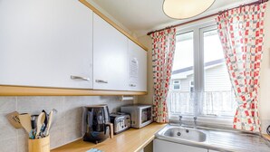 A compact kitchen with white cabinets, a coffee maker, a toaster, and a sink.