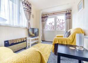 Une chambre d’hôtel avec un lit, un canapé, une télévision, une petite table et une fenêtre avec des rideaux.