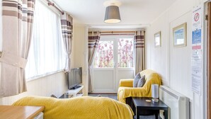 A room with two beds, a TV, a table, a lamp, and a window with curtains.