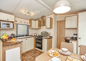 A compact kitchen with a microwave, oven, and wooden cabinets.