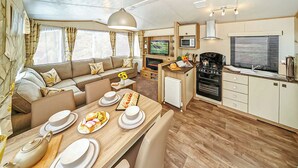 A cozy RV interior with a dining area, kitchenette, and a sofa. - 12ft-wide caravan with one double and one twin. (Silloth)