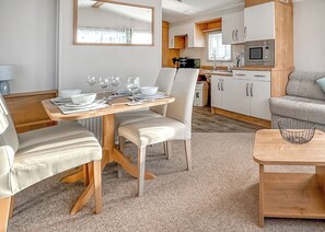 A compact kitchen with a microwave, cabinets, and a dining area with a table set for four.