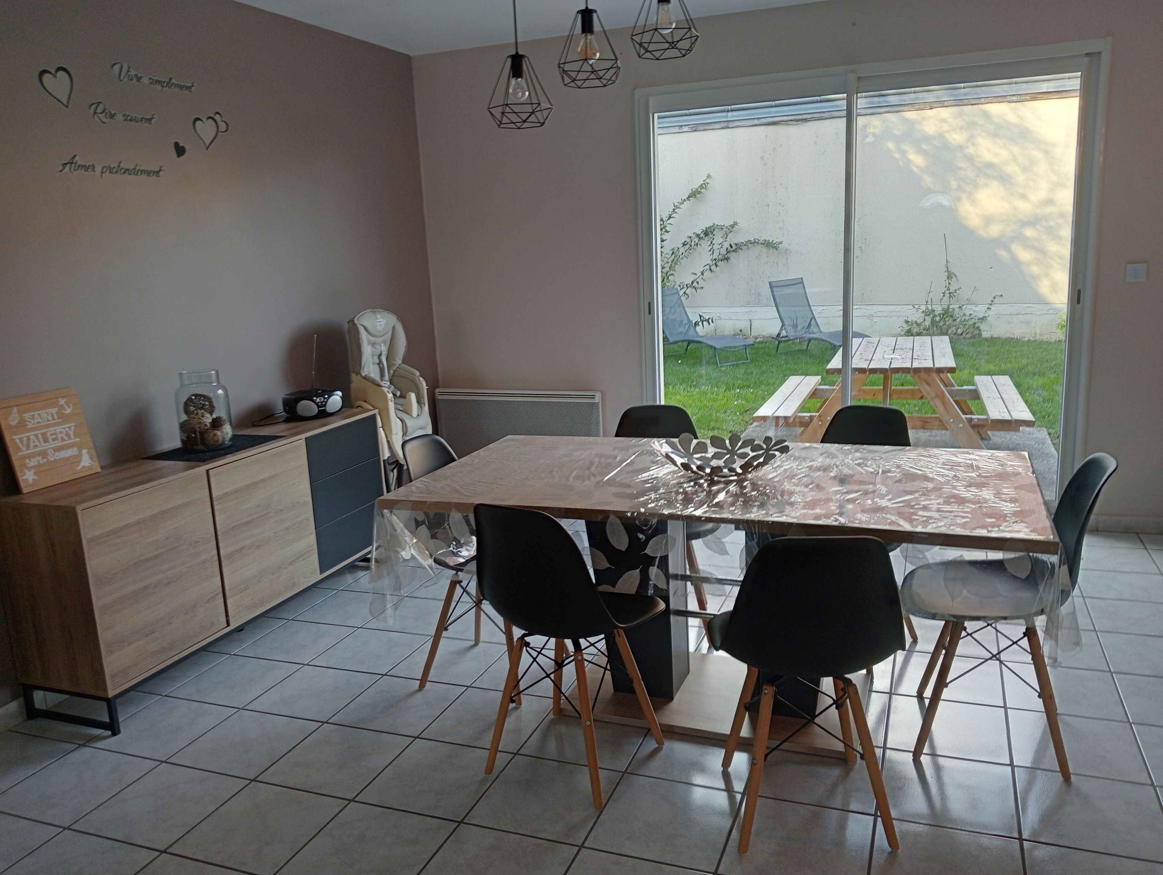 A modern kitchen with a dining table, chairs, and a view of the outdoors.
