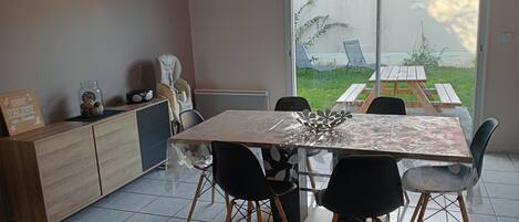 A modern kitchen with a dining table, chairs, and a view of the outdoors.