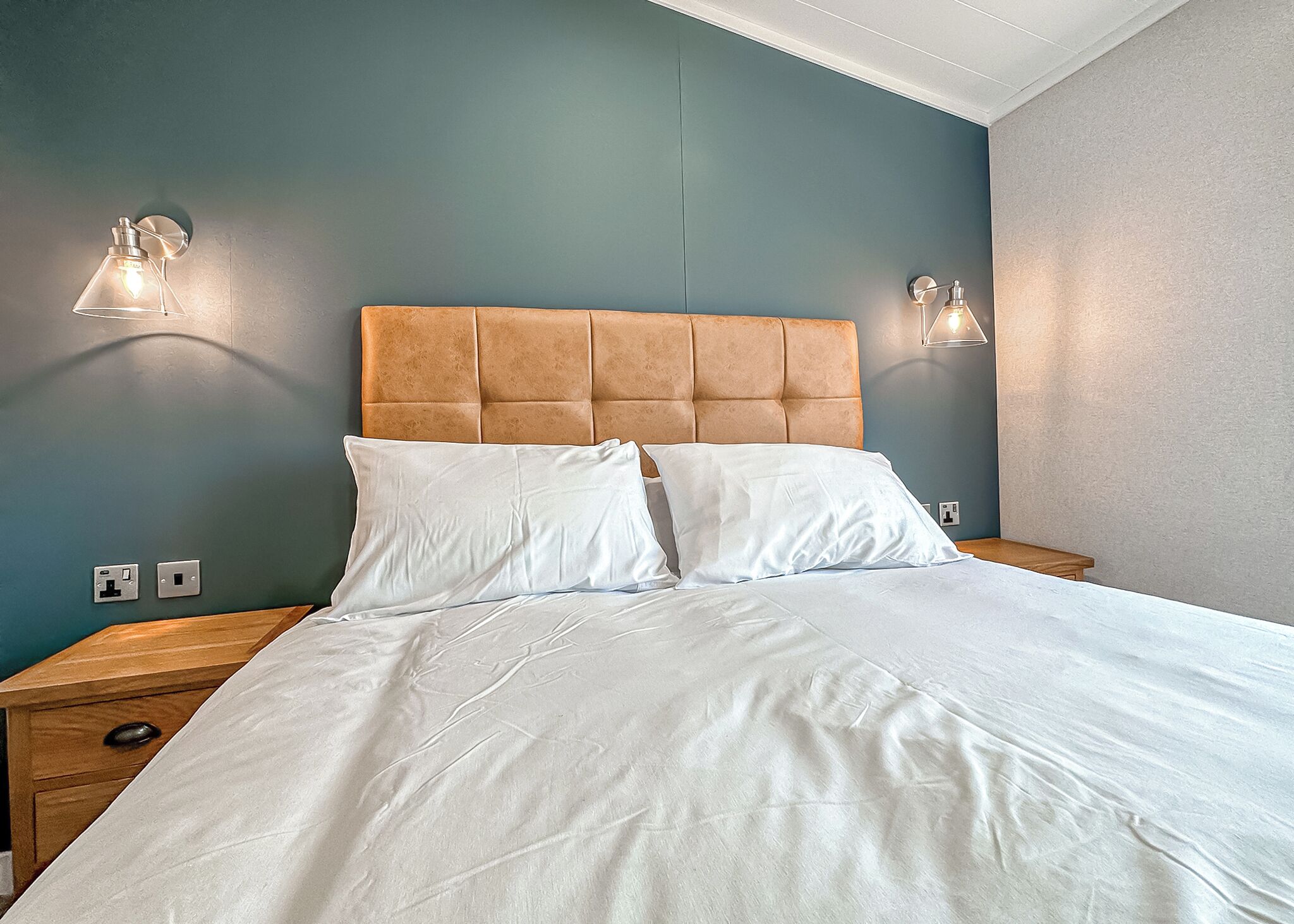 A neatly made bed with white linens, a tufted headboard, and two bedside lamps.