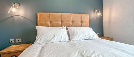 A neatly made bed with white linens, a tufted headboard, and two bedside lamps.