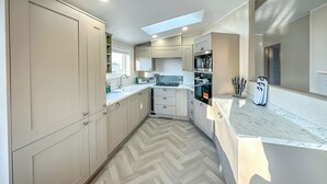 Una cocina moderna con suelo de espiga, armarios empotrados, una isla central y un tragaluz.