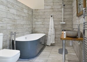 A modern bathroom with a freestanding bathtub, a shower, a toilet, and a vanity with a basin.