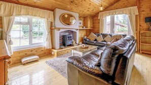 A log cabin interior with a fireplace, leather sofa, and wooden floors.