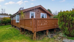 A wooden cabin with a deck, a window, and a door.