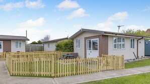 A row of mobile homes with a wooden fence in front, a picnic table, and a small shed. - 1 bedroom accommodation in Anderby Creek, Mablethorpe (Anderby Creek, Mablethorpe)