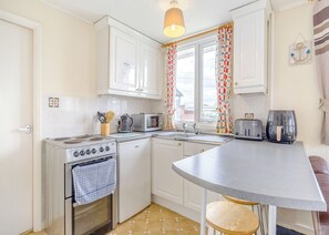 A compact kitchen with a stove, microwave, toaster, and air fryer.