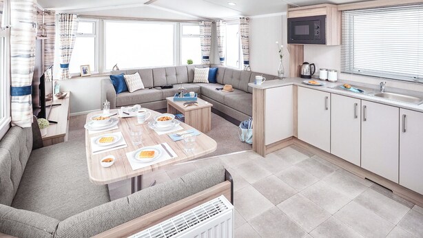 A compact RV interior with a dining area, kitchenette, and a sofa. - 2 bedroom accommodation in Cresswell beach (Cresswell beach)