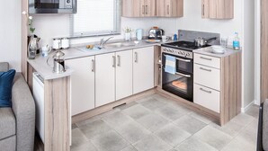 A compact kitchen with a microwave, stove, oven, and a sink. - 2 bedroom accommodation in Cresswell beach (Cresswell beach)